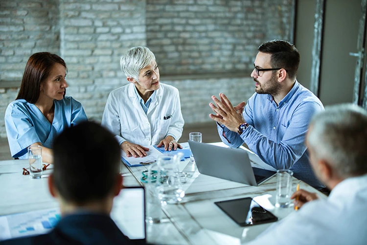 A medical broker at a table with healthcare professionals discussing the process of selling a medical practice