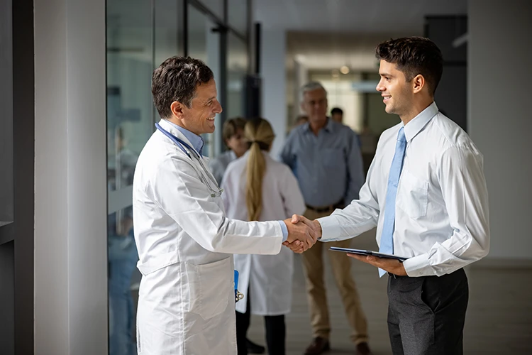 A medical broker shaking hands with a doctor at an appointment to discuss selling a practice