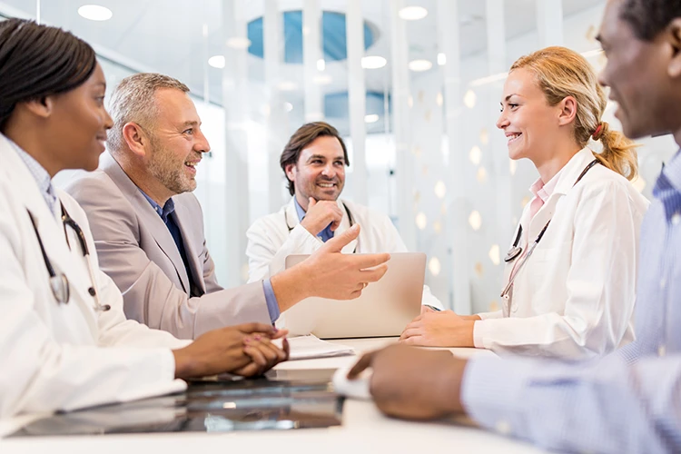 A medical broker talking with a group of doctors at a table about the process of buying a practice