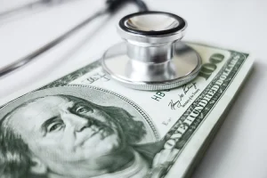 A stethoscope on top of a stack of one hundred dollar bills