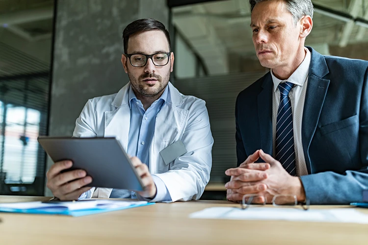 Medical practice owners reviewing add-backs and business info on a tablet
